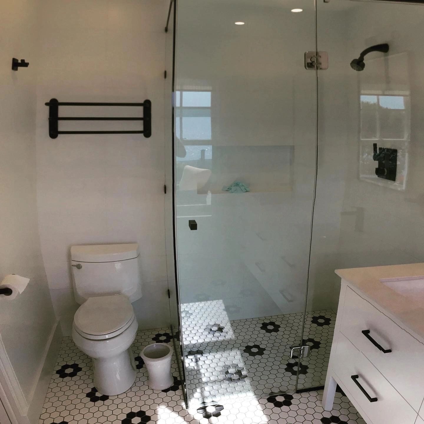 Bathroom renovation — frameless glass shower with hex tile floor and black fixtures
