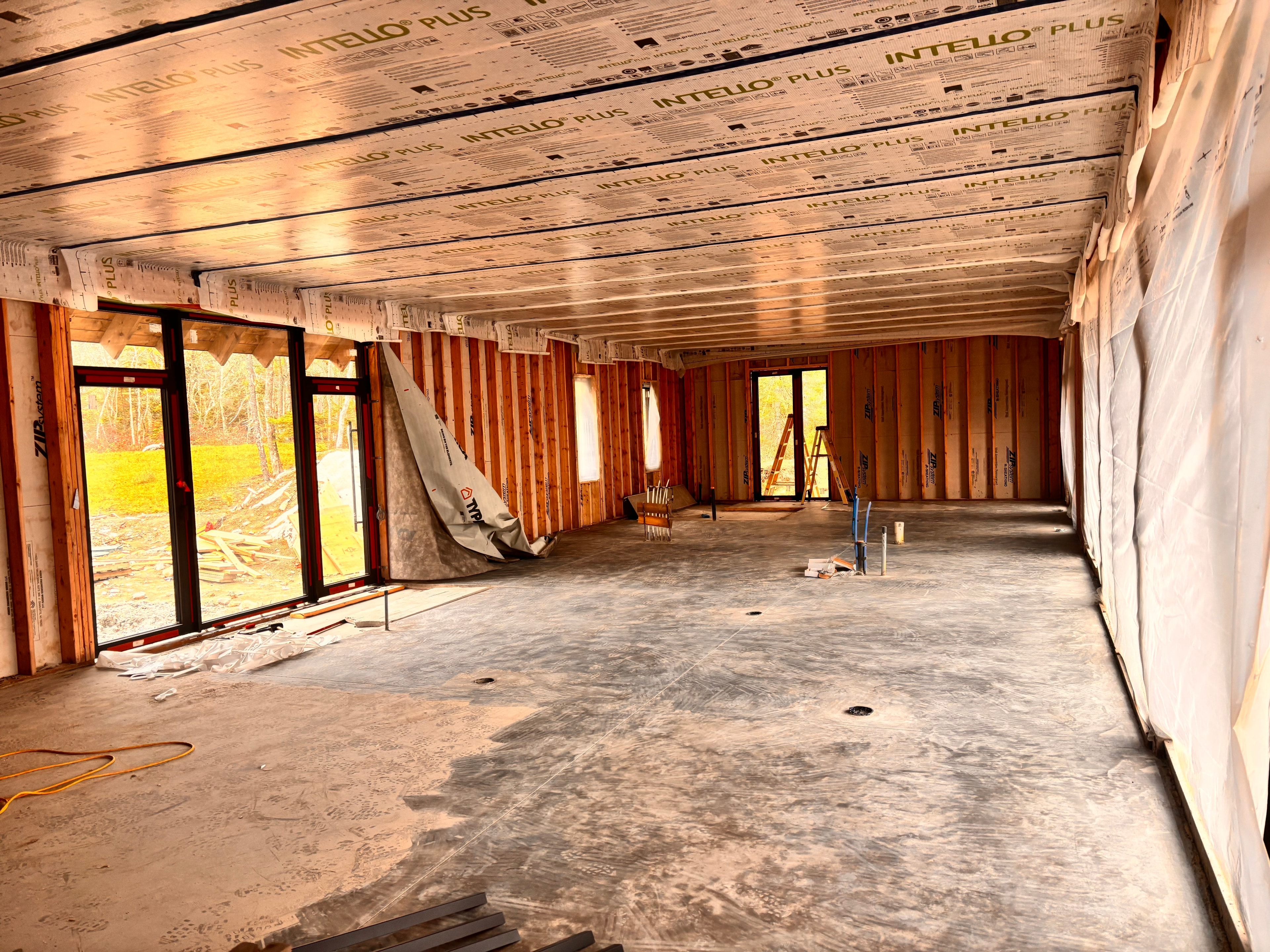 Sunroom addition under construction — timber framing, vapour barrier, and floor-to-ceiling glazing