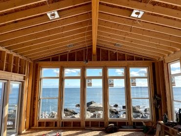 Coastal home interior under construction — timber framing and ocean view windows