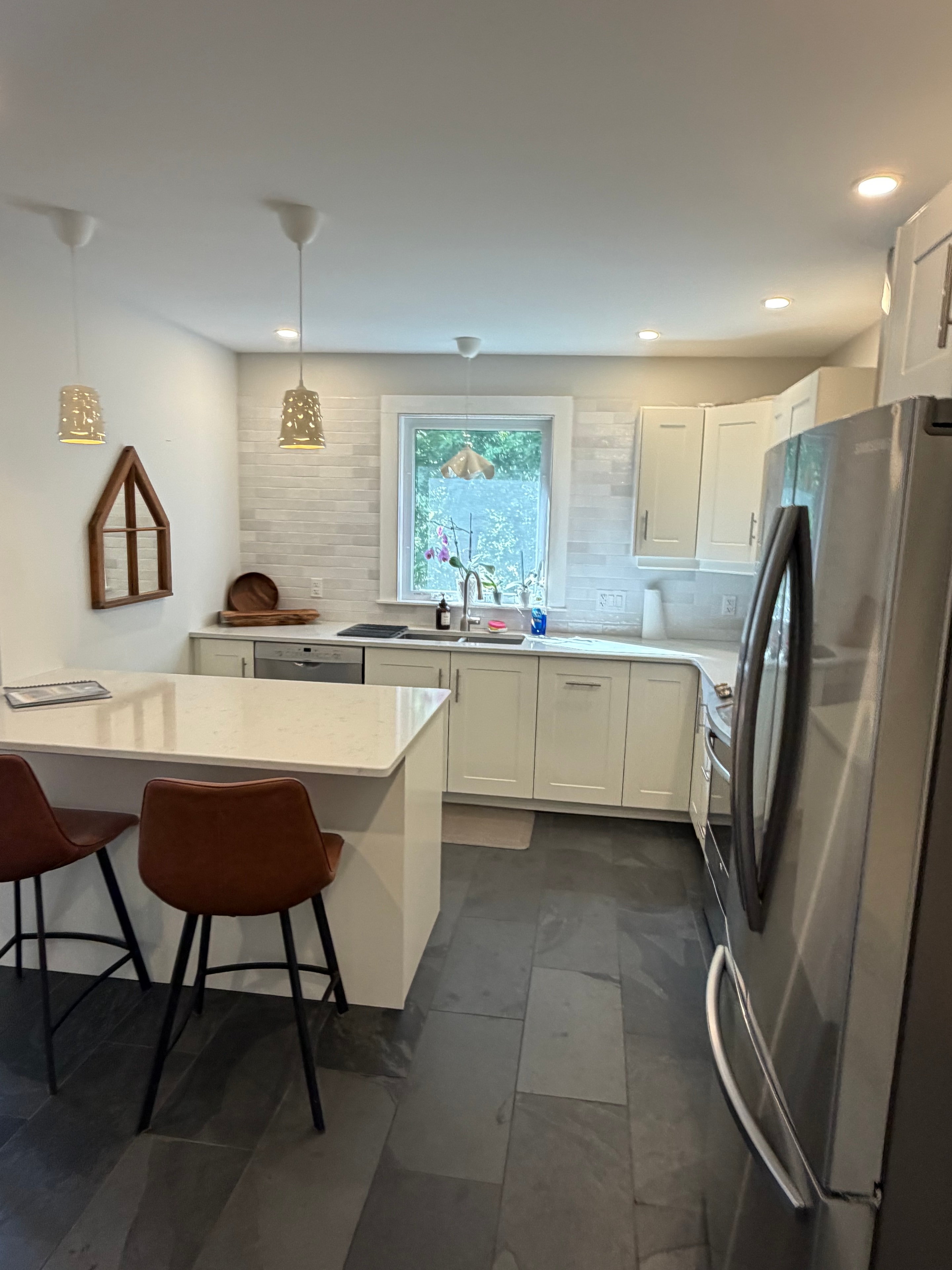 Renovated kitchen — second angle showing island seating and slate tile floor