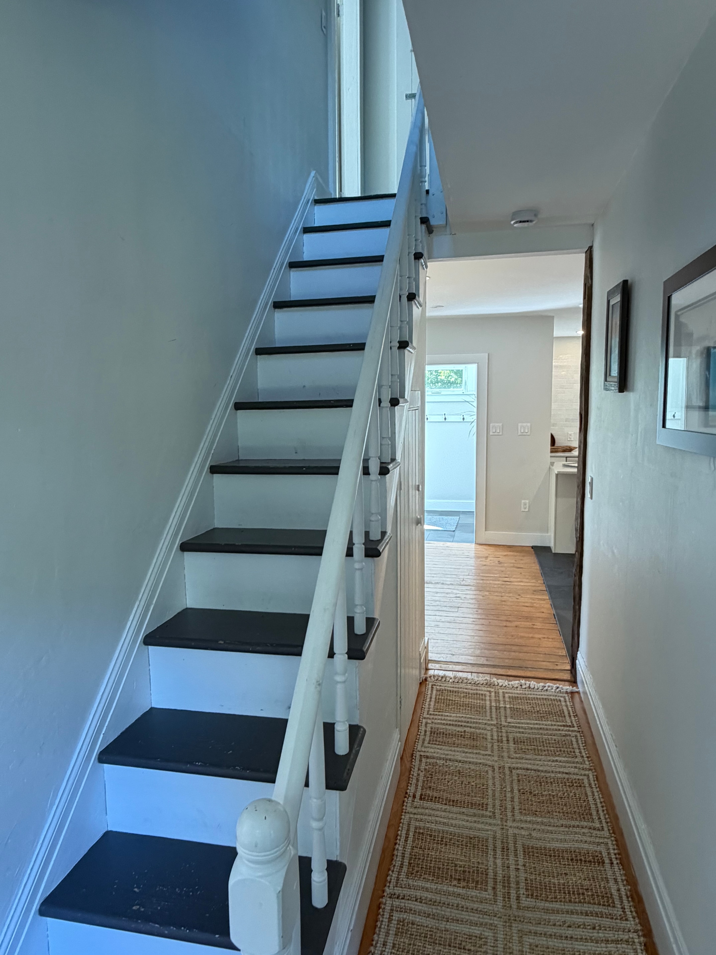 Renovated staircase and hallway — black treads, white risers, hardwood floors